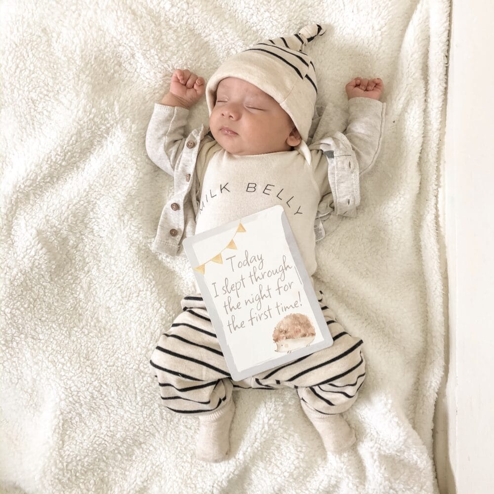 A newborn baby laying on a blanket with a card.