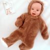 A baby in a bear costume laying on a bed.