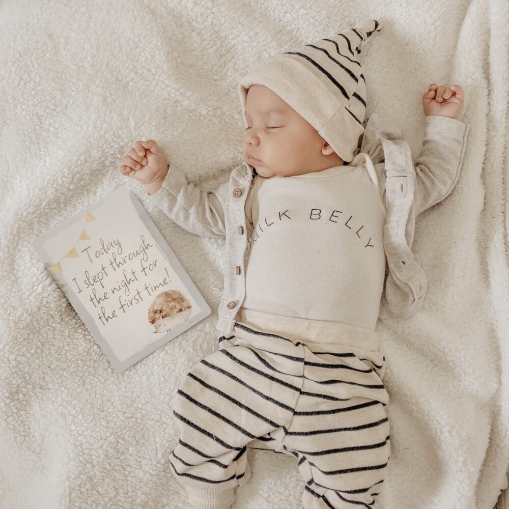 A baby laying on a blanket with a book on it.