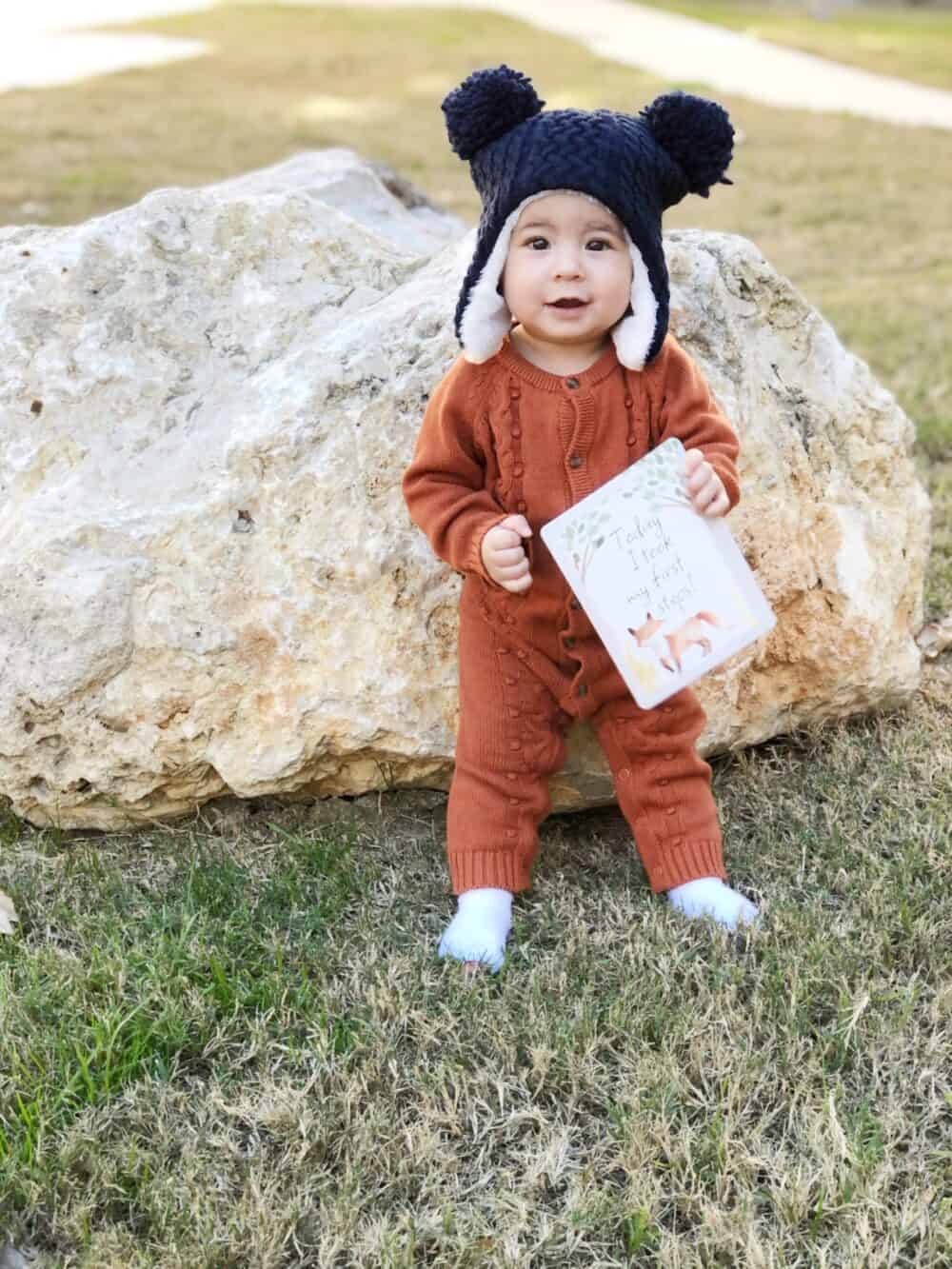 A baby wearing a hat and holding a book.