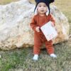 A baby wearing a hat and holding a book.