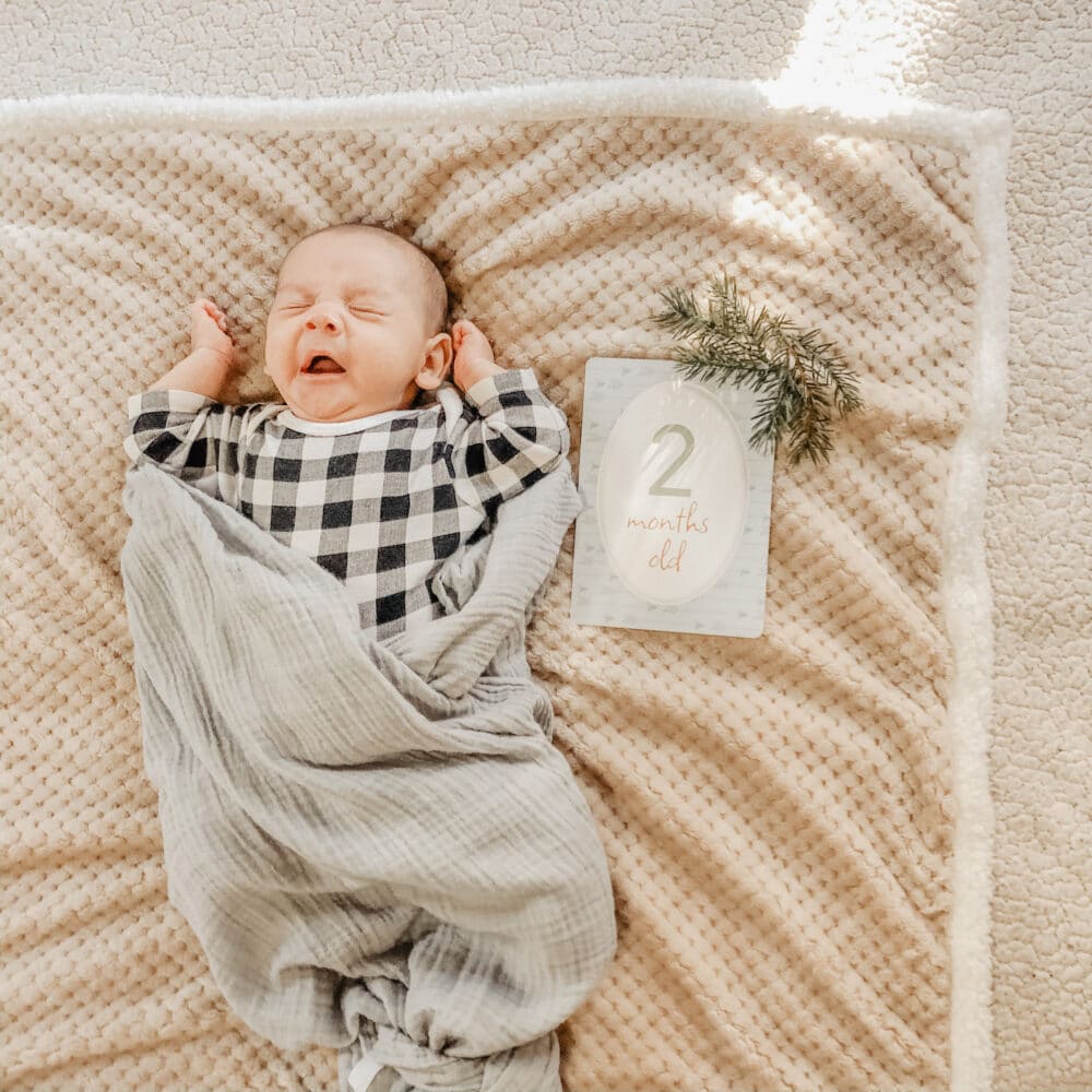 A baby sleeping on a blanket with a number sign.