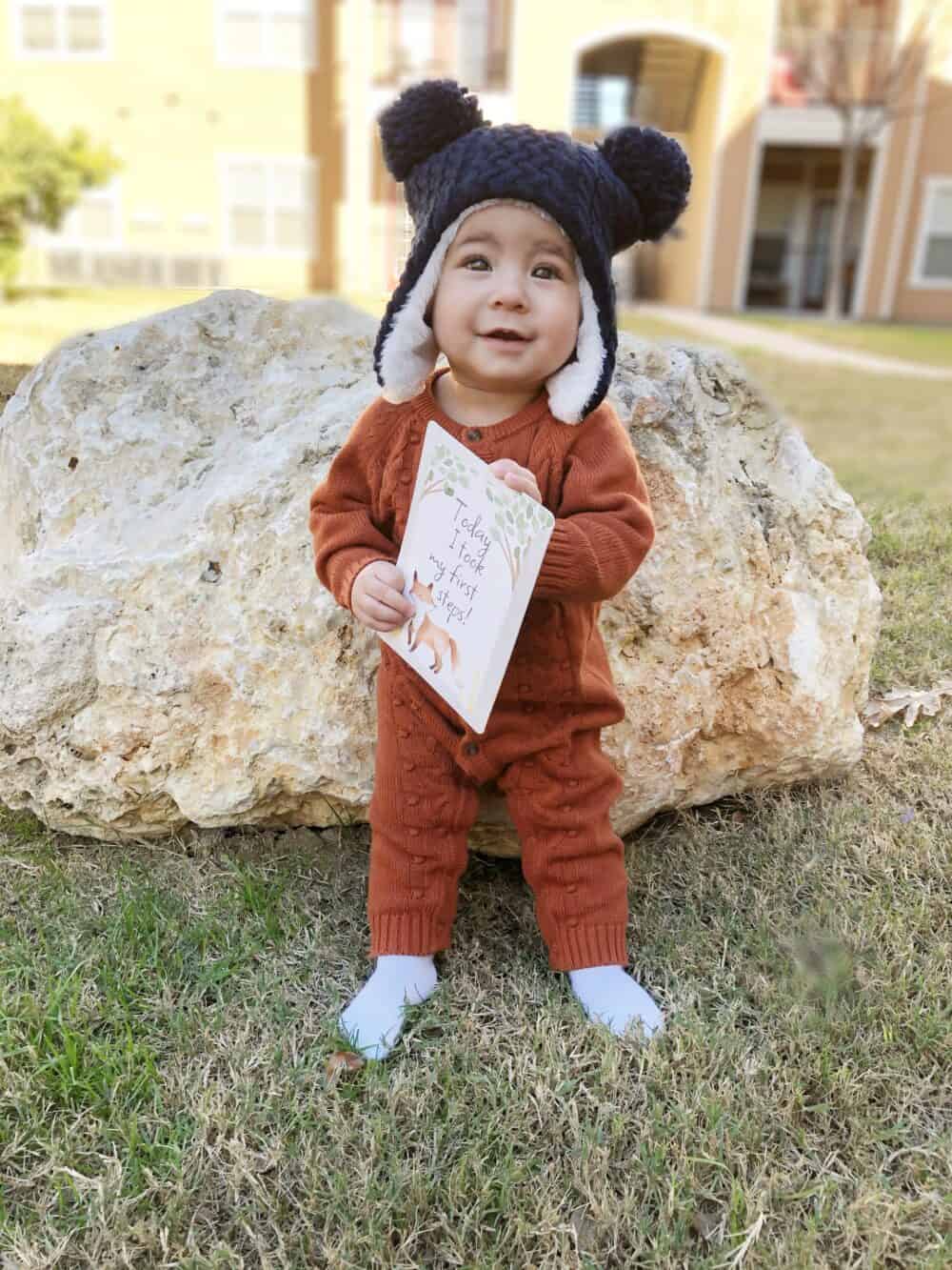 A baby wearing a hat and holding a book.