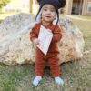 A baby wearing a hat and holding a book.