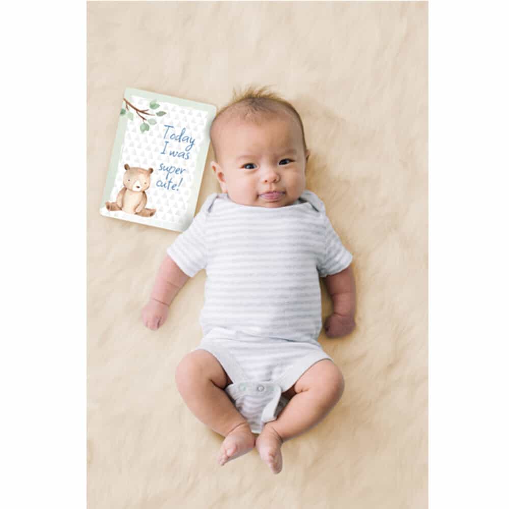 A baby is laying on a blanket with a book on it.