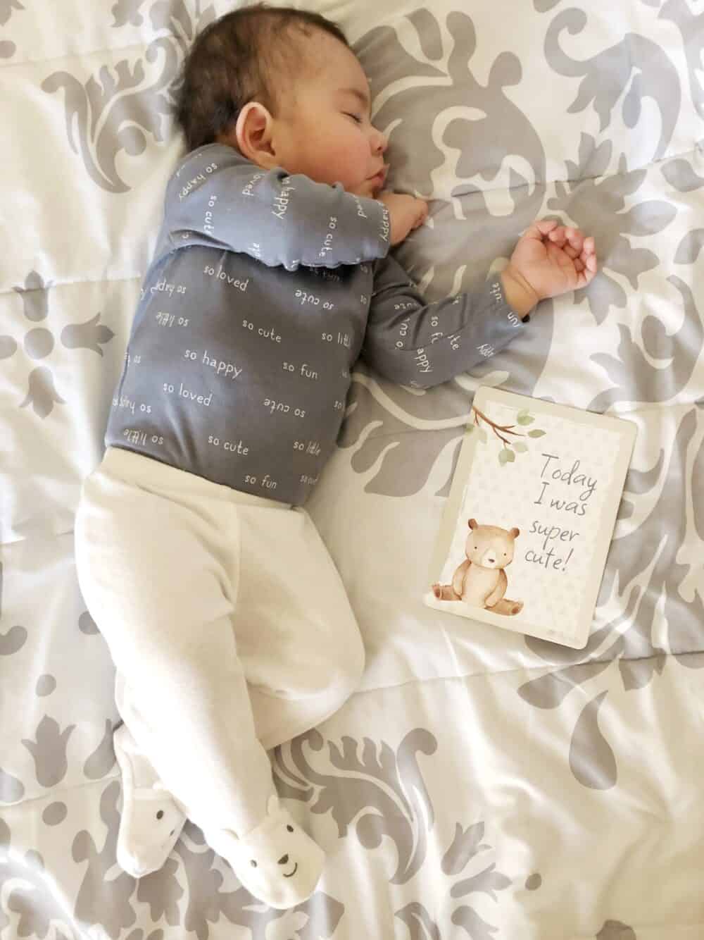 A baby sleeping on a bed next to a book.