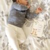 A baby sleeping on a bed next to a book.