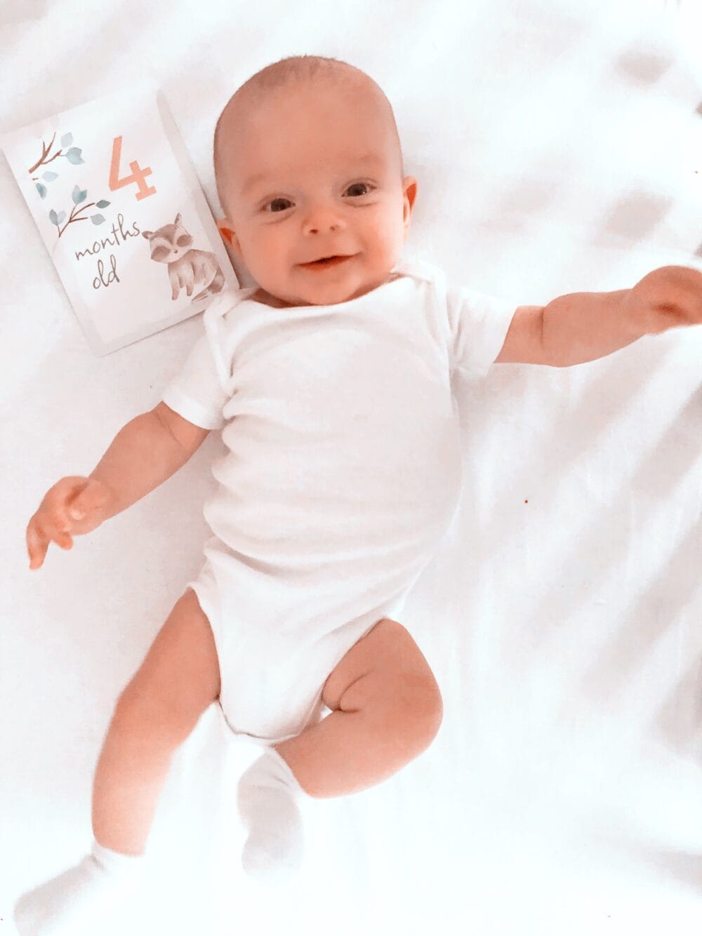 A baby laying on a bed with a book on it.