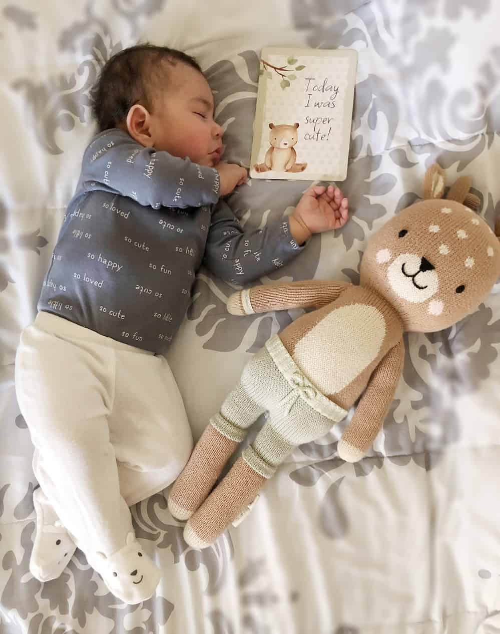 A baby sleeping next to a stuffed deer.