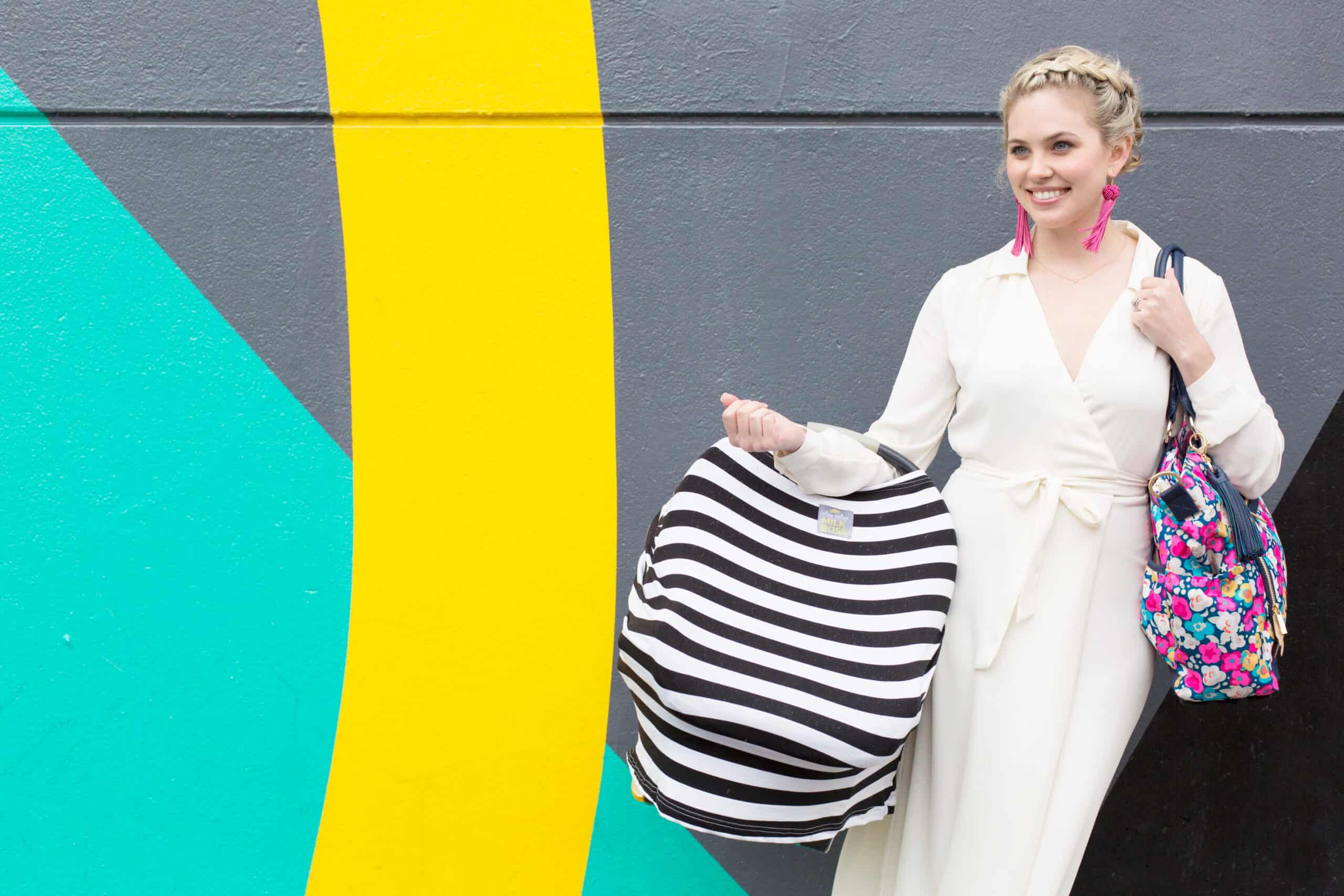 A woman in a white dress standing next to the Mom Boss™ 4-IN-1 Multi-Use Nursing Cover & Scarf.