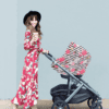 A woman in a floral dress pushing a Mom Boss™ 4-IN-1 Multi-Use Nursing Cover & Scarf stroller.