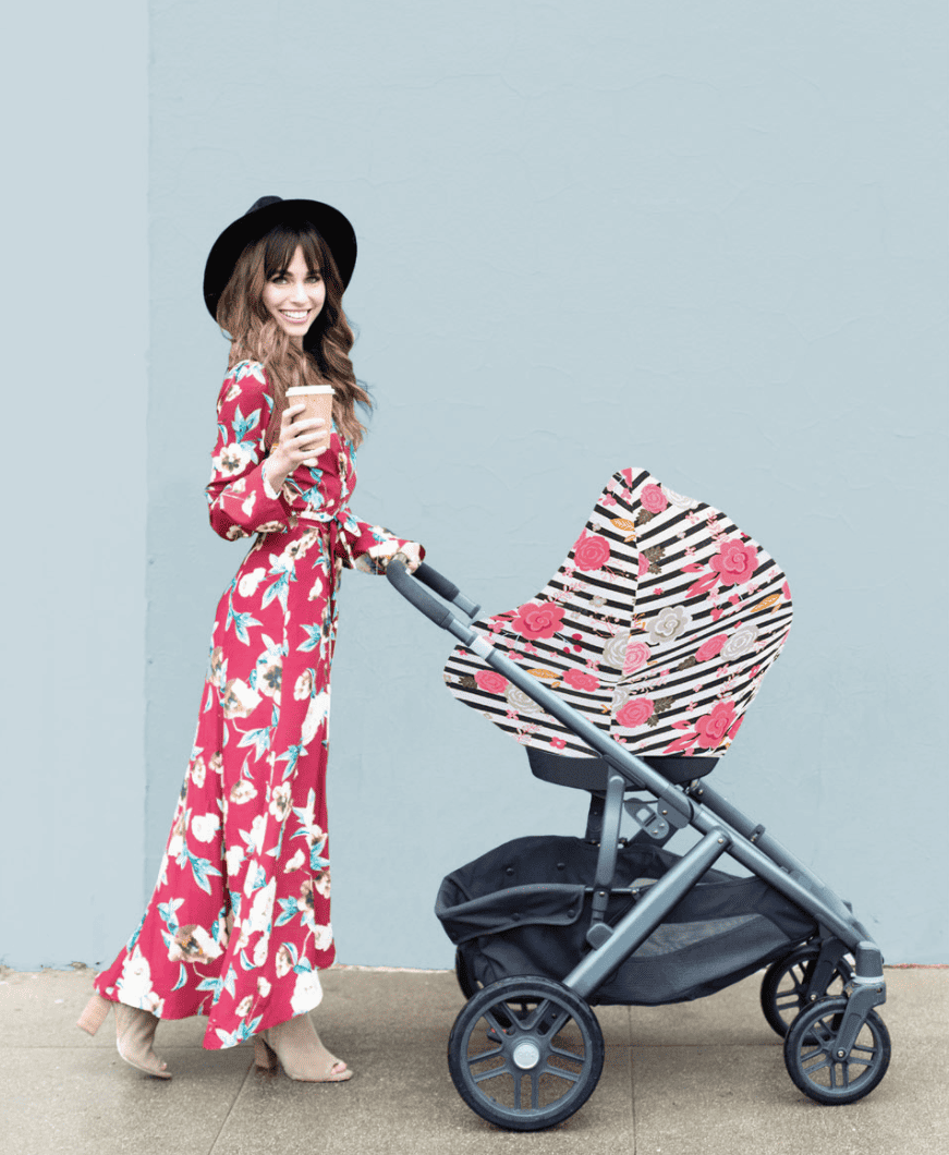 A woman in a floral dress pushing a Mom Boss™ 4-IN-1 Multi-Use Nursing Cover & Scarf stroller.