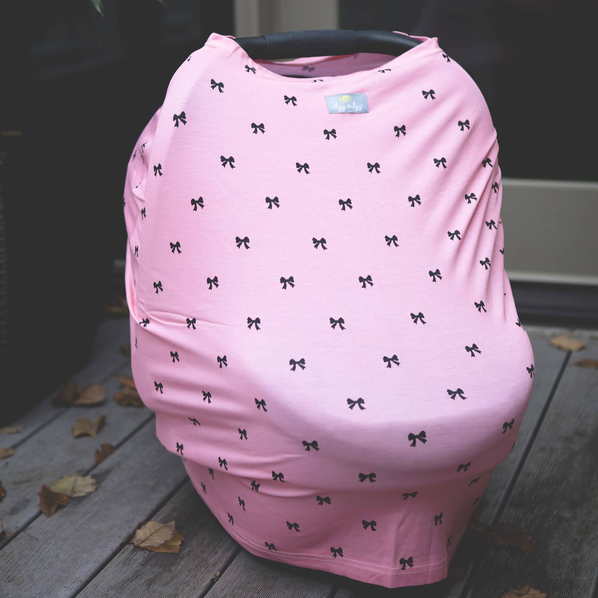 A pink Mom Boss™ 4-IN-1 Multi-Use Nursing Cover & Scarf with black bows on it.