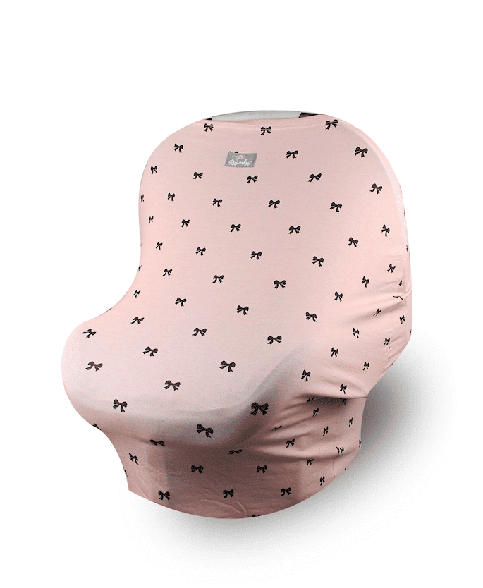 A pink Mom Boss™ 4-IN-1 Multi-Use Nursing Cover & Scarf with black bows on it.