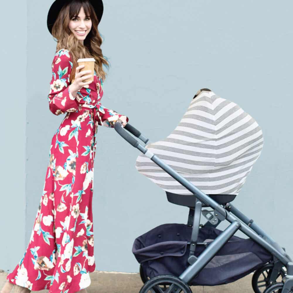 A woman in a floral dress pushing a Mom Boss™ 4-IN-1 Multi-Use Nursing Cover & Scarf stroller.