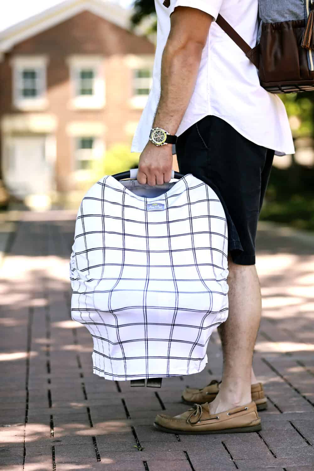 A man carrying a Mom Boss™ 4-IN-1 Multi-Use Nursing Cover & Scarf on a sidewalk.