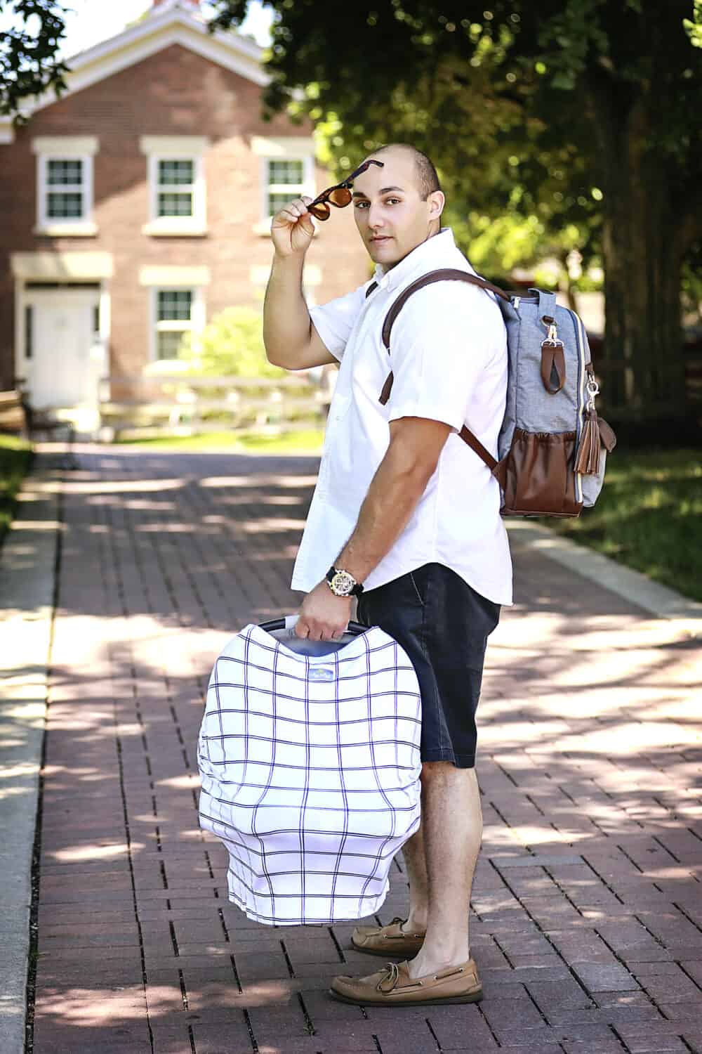 A man with a Mom Boss™ 4-IN-1 Multi-Use Nursing Cover & Scarf holding a suitcase.