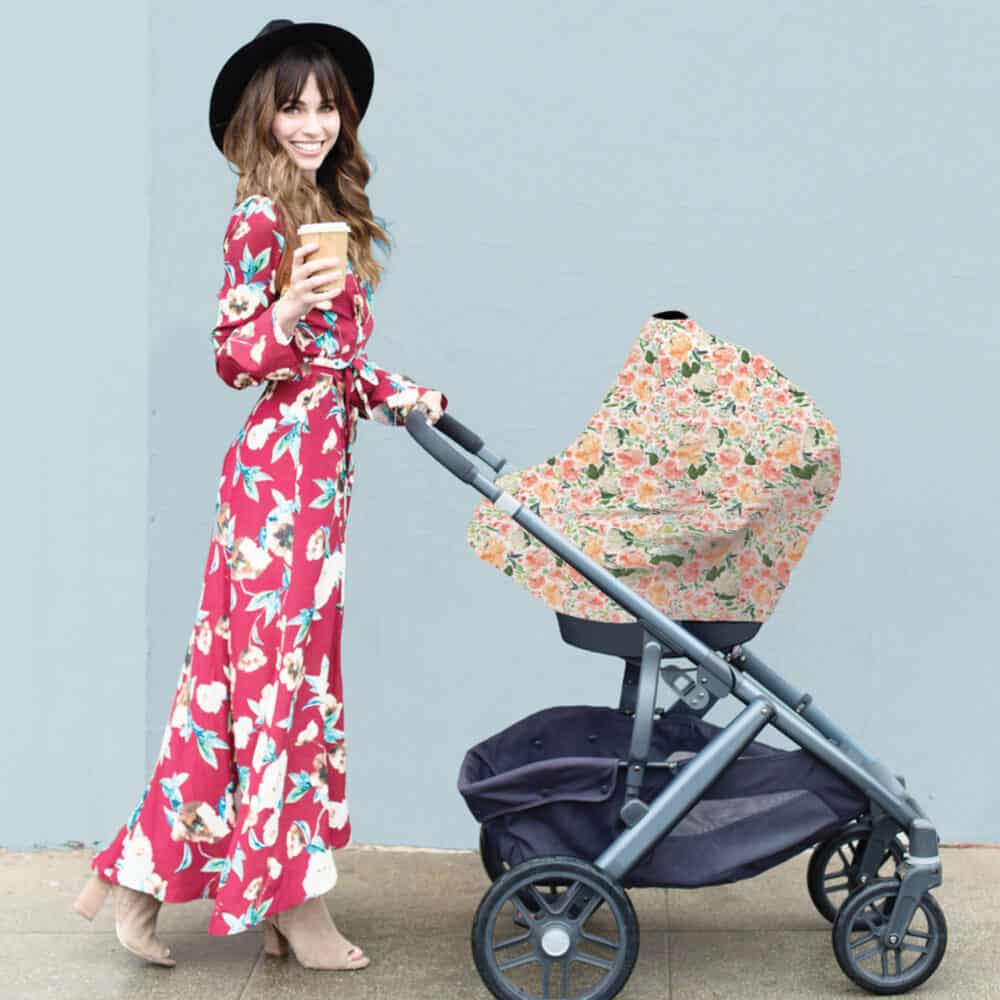 A woman in a floral dress pushing a Mom Boss™ 4-IN-1 Multi-Use Nursing Cover & Scarf.