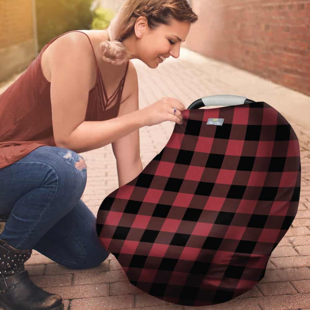 A woman kneeling down with a Mom Boss™ 4-IN-1 Multi-Use Nursing Cover & Scarf.