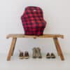 A red and black plaid Mom Boss™ 4-IN-1 Multi-Use Nursing Cover & Scarf on a wooden bench.