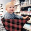 A baby sitting in a shopping cart with a Mom Boss™ 4-IN-1 Multi-Use Nursing Cover & Scarf.