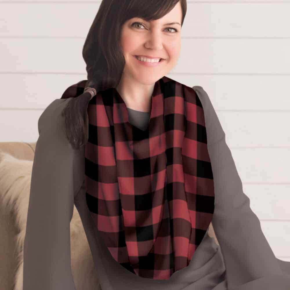 A woman sitting on a couch wearing a Mom Boss™ 4-IN-1 Multi-Use Nursing Cover & Scarf.