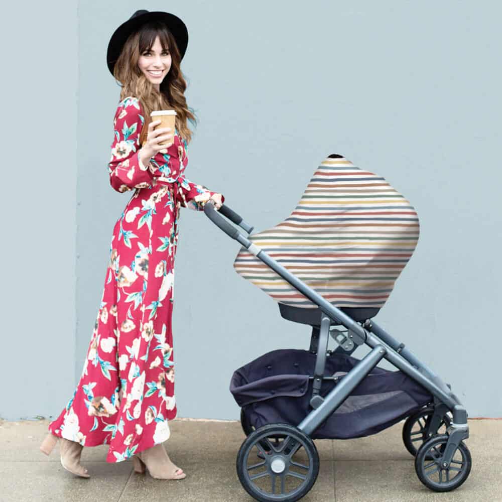 A woman in a floral dress pushing a Mom Boss™ 4-IN-1 Multi-Use Nursing Cover & Scarf stroller.