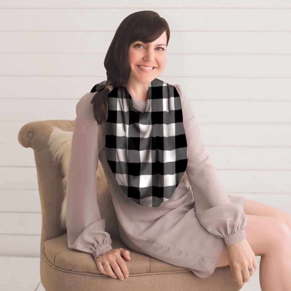 A woman sitting on a chair wearing a Mom Boss™ 4-IN-1 Multi-Use Nursing Cover & Scarf.