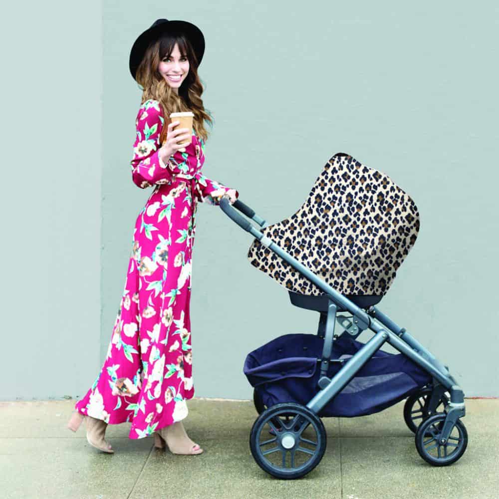 A woman pushing a stroller with a Mom Boss™ 4-IN-1 Multi-Use Nursing Cover & Scarf.