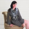 A woman sitting on a chair wearing a Mom Boss™ 4-IN-1 Multi-Use Nursing Cover & Scarf.