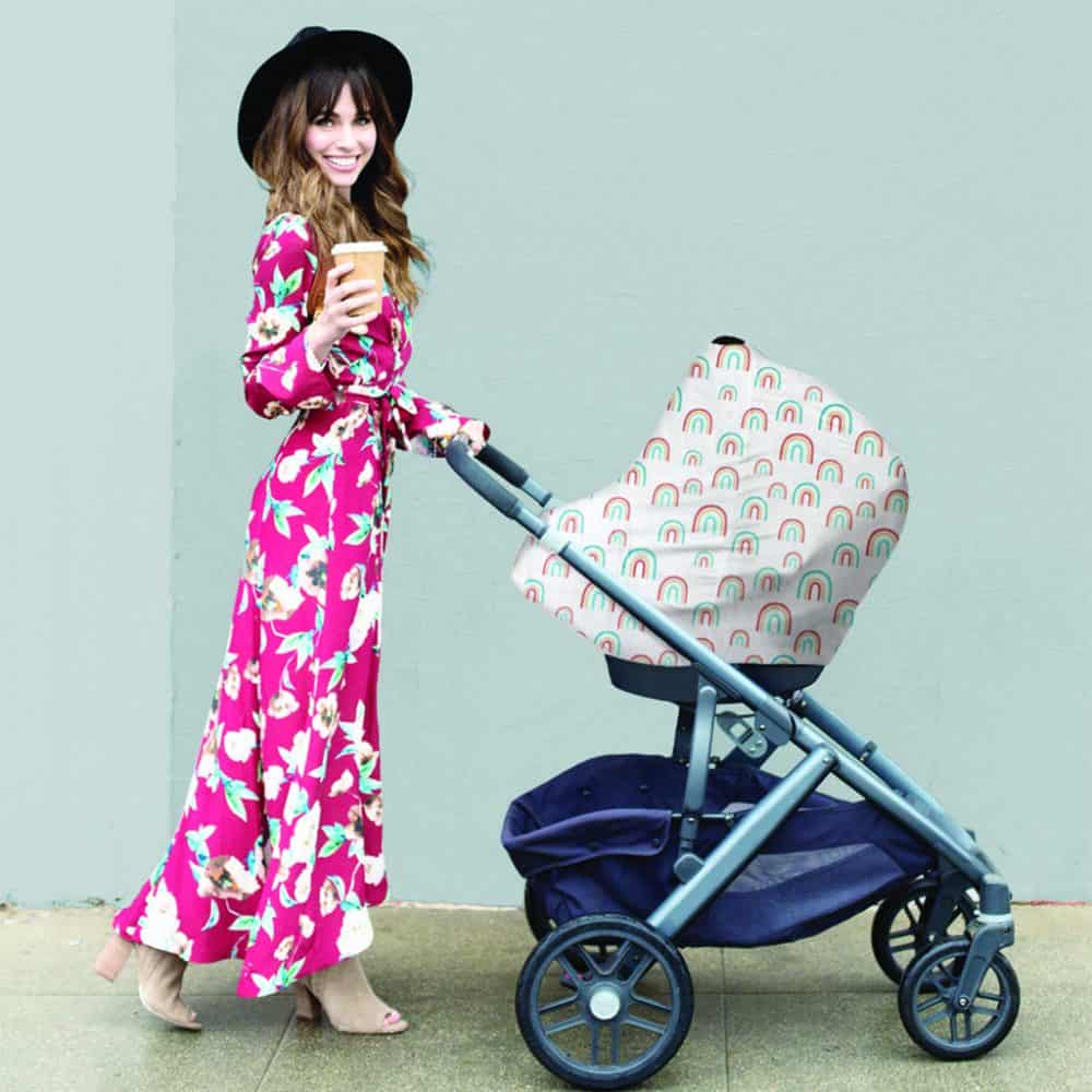 A woman in a floral dress pushing a Mom Boss™ 4-IN-1 Multi-Use Nursing Cover & Scarf.