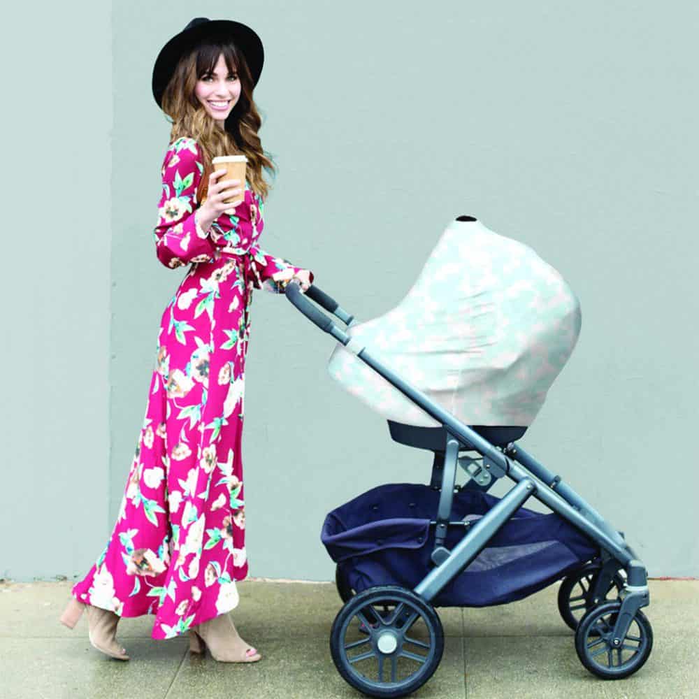 A woman in a floral dress pushing a Mom Boss™ 4-IN-1 Multi-Use Nursing Cover & Scarf stroller.