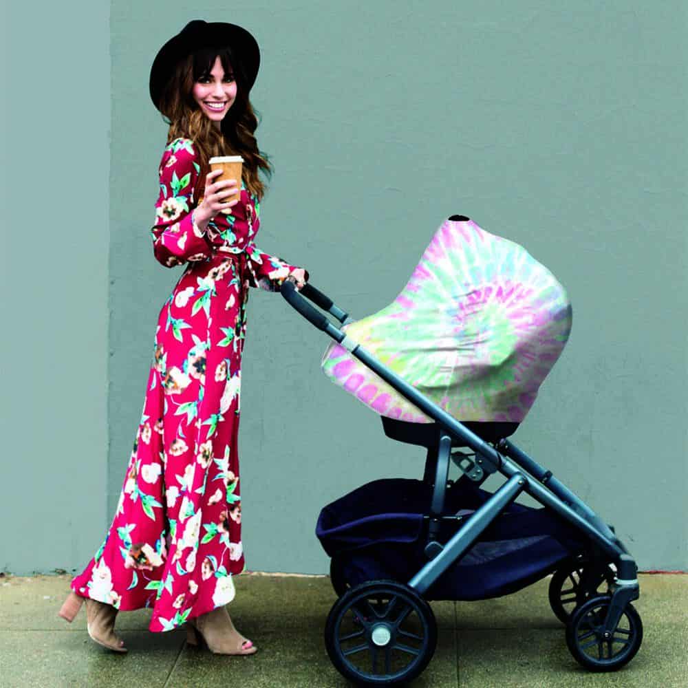 A woman in a Mom Boss™ 4-IN-1 Multi-Use Nursing Cover & Scarf pushing a stroller.