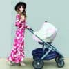 A woman in a Mom Boss™ 4-IN-1 Multi-Use Nursing Cover & Scarf pushing a stroller.