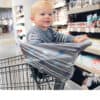 A baby sitting in a Mom Boss™ 4-IN-1 Multi-Use Nursing Cover & Scarf in a grocery store.