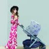 A woman pushing a stroller with the Mom Boss™ 4-IN-1 Multi-Use Nursing Cover & Scarf and a cup of coffee.