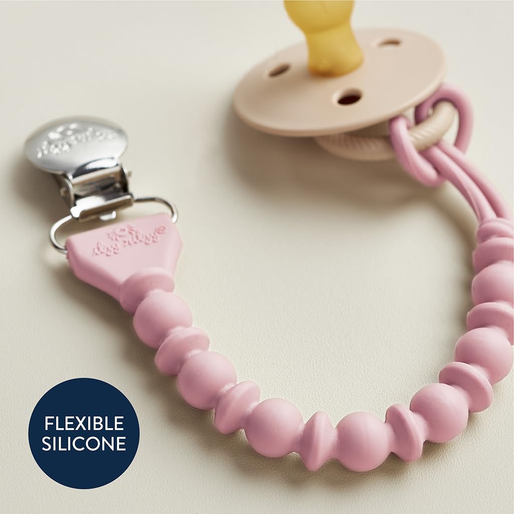 A pacifier with a light pink, beaded silicone strap and a metal clip attached to a beige round holder on a white surface. Text on image reads: "FLEXIBLE SILICONE.