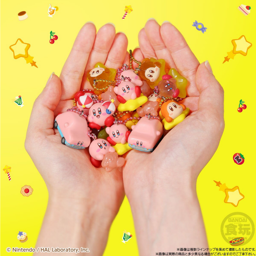 kirby-shokugan-2 Two hands are holding a variety of Kirby Mascot Shokugan Wave 1 Box Keychain Collection Key Chains Without Gum against a bright yellow background decorated with small graphics.