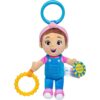 Ms Rachel Official Sensory Take-Along Toy Herbie Doll—features brown hair, blue overalls, a pink headband, and holds a yellow teething ring plus a blue tag that reads “Shake Shake,” with a blue plastic stroller clip attached to its head. Suitable for babies 3 months and up.
