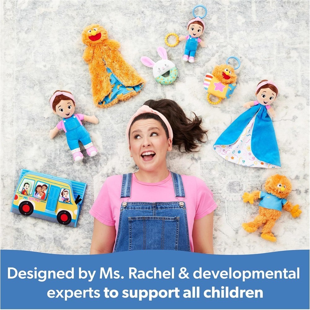 A woman in pink and denim overalls lies on the floor, surrounded by plush toys and the Ms Rachel Official Sensory Take-Along Toy Herbie Doll Baby Teether Rattle Stroller Clip (for 3 months+). A blue banner below reads: “Designed by Ms. Rachel & developmental experts to support all children.”.