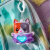 nanomals-113 A Hasbro Nano mals Purrnelope Calico Kitty electronic pet keychain, shaped like a cat with a glowing heart, is attached to the zipper of a shiny, iridescent backpack.