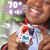 nanomals-116 A person is holding a Hasbro Nano mals Purrnelope Calico Kitty Electronic Pet Interactive Fidget Toy Nanomals, a small and colorful electronic toy cat. The image features symbols for sound and music, along with the text “70+” displayed above the toy.