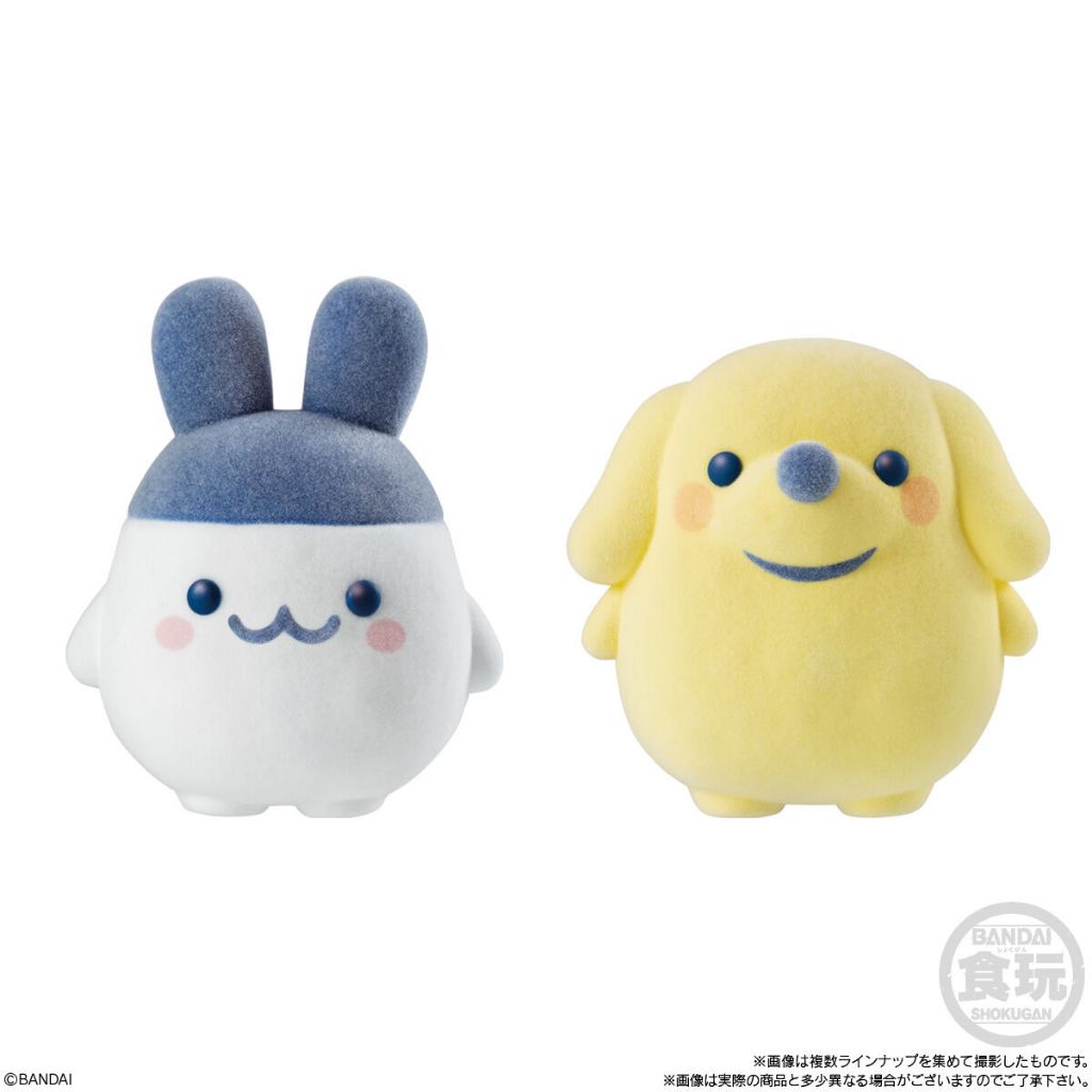 tamagotchi-frienddoll-5 Two round plush figures from the Bandai Tamagotchi Otomodachi Friend Doll Flocked Figure collection are shown: one resembles Mametchi, white with blue bunny-like ears, and the other resembles Kuchipatchi, yellow with floppy ears and a blue nose.