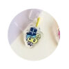 tamagotchi-uni-dustplug-3 A Tamagotchi Uni keychain dust plug featuring a cartoon animal face with a blue hat and bowtie, attached to a clear acrylic charm for mobile phones with Type C ports.